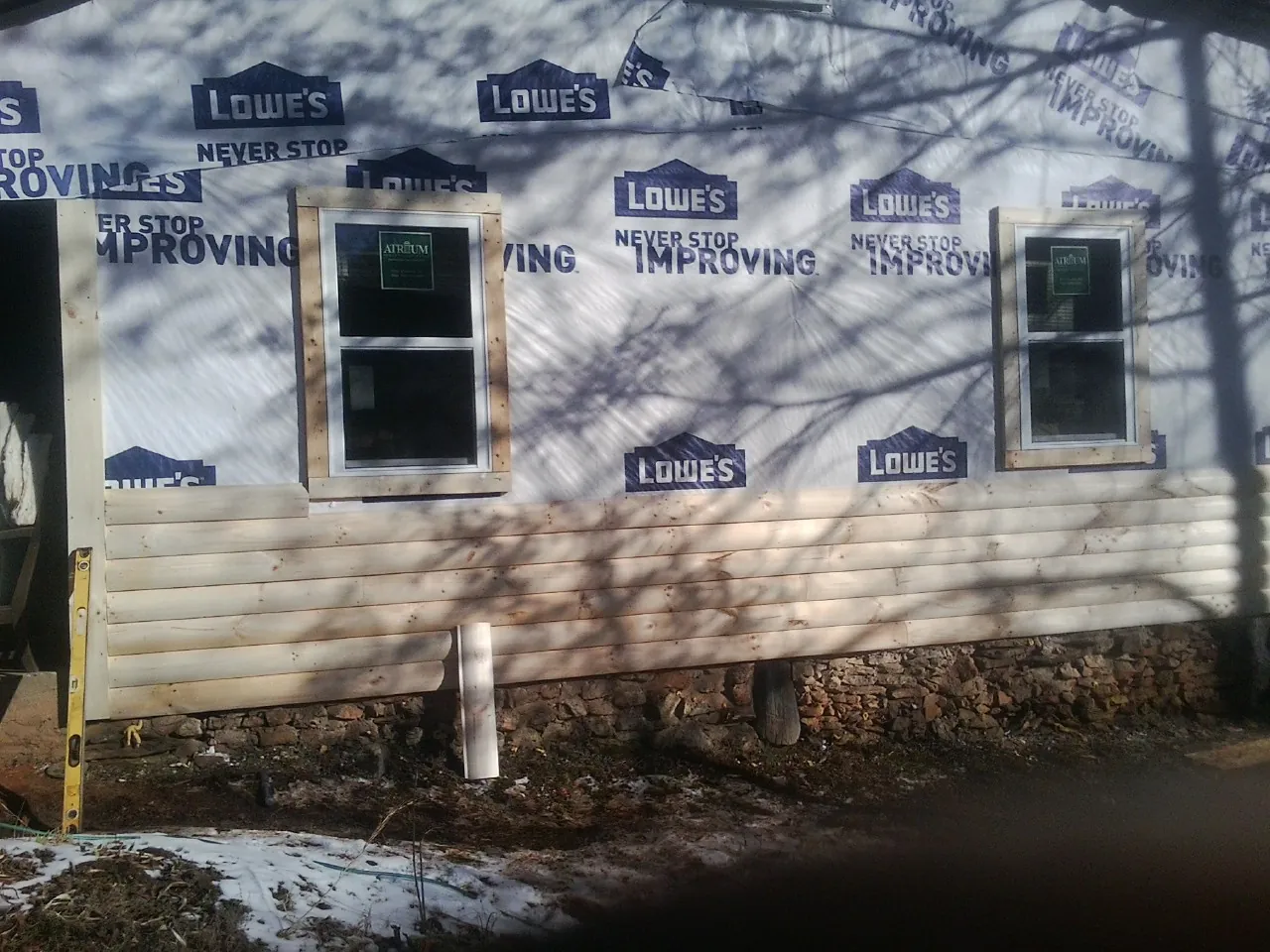 House wrap and new log siding going up on an exterior wall in Schuylerville