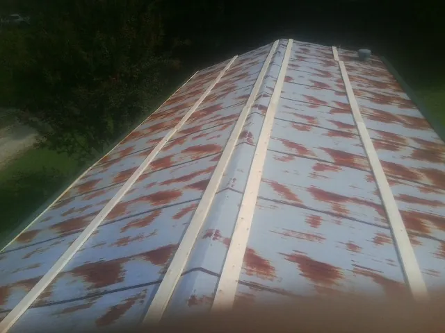 Rusted metal roof panels with new wood purlins before replacement — Storm Damage Roof Repair in Schuylerville by Roofing Brothers