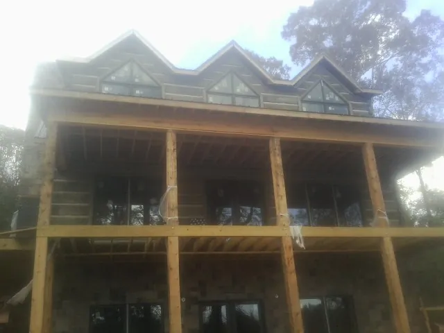 Dormers and porch framing on a large log home under construction — Roof Coating work by our crew in Schuylerville