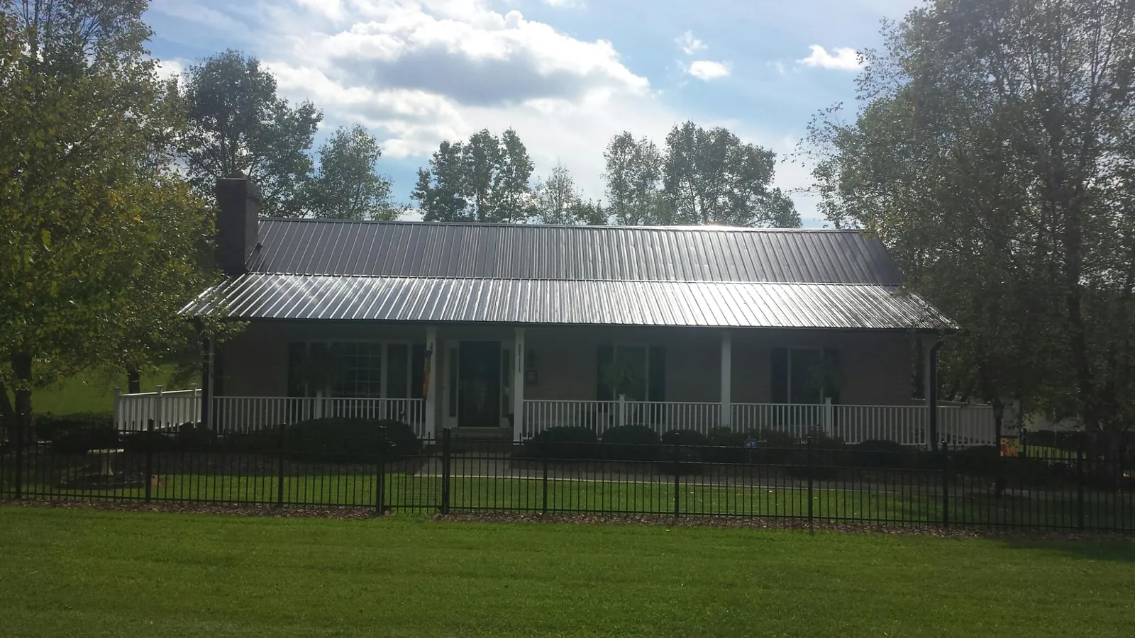 Gray metal roof on a brick ranch with a full width front porch — Gutter Guard Installation work by our crew in Schuylerville