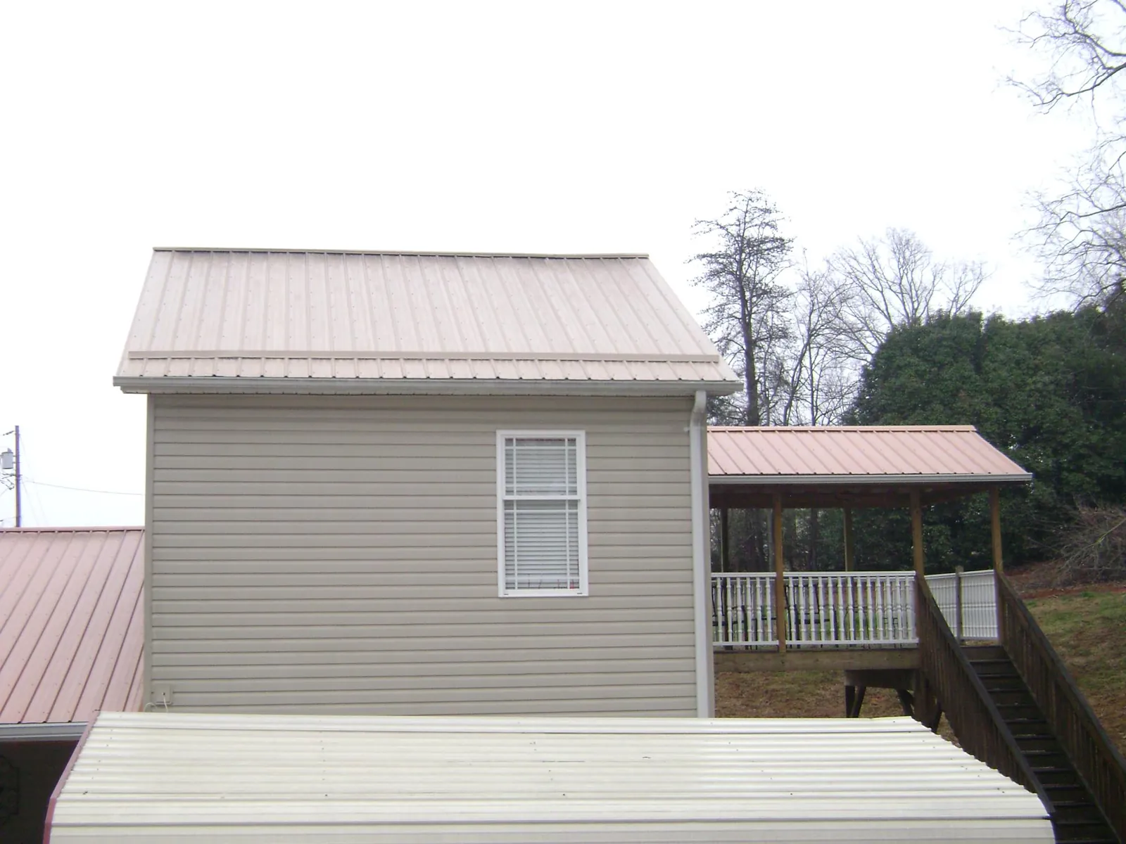 Tan metal roofs on a two story addition and attached porch, from a Roof Replacement job in Schuylerville