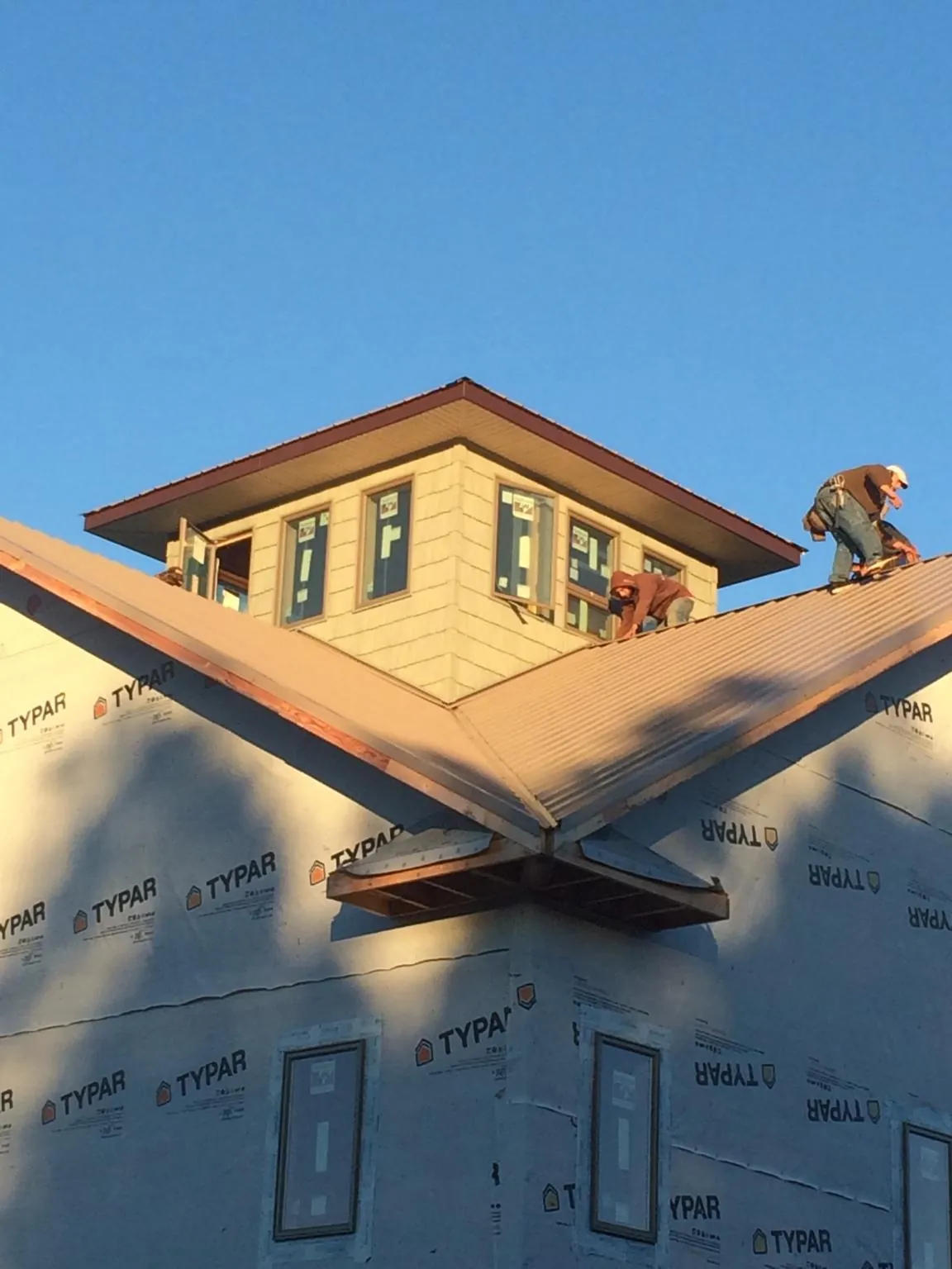 Roofers working around a rooftop cupola on a new metal roof at sunset — Roof Waterproofing in Schuylerville by Roofing Brothers